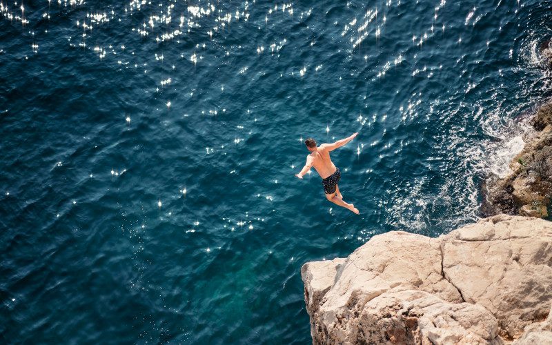 Tourists dive from the cliffs surrounding the ancient city of Dubrovnik